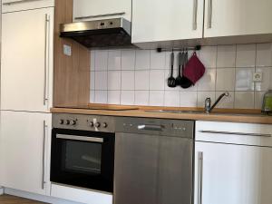 a kitchen with white cabinets and a stainless steel dishwasher at Ferienwohnung De Krabb in Dorum