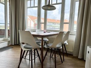 a dining room table with white chairs and a large window at Ferienwohnung De Krabb in Dorum