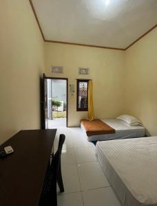 ein Zimmer mit zwei Betten und einem Schreibtisch und einem Tisch in der Unterkunft Victoria Homestay in Pulau Lutung