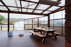 a patio with a wooden table and a bench at Family Comfort in the Stunning Sisters Beach in Sisters Beach