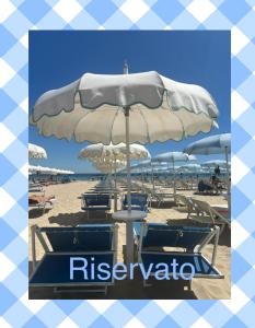 Un grupo de sillas y una sombrilla en la playa. en Casa Antonelli --- spiaggia inclusa --, en San Benedetto del Tronto