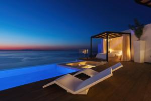 a bedroom with a view of the ocean at night at Emerald Villas & Suites - The Finest Hotels Of The World in Agios Nikolaos