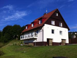 a large white house with a red roof on a hill at Villa Maximus in Jáchymov