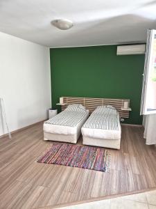 two beds in a room with a green wall at YES Varna Studios in Varna City