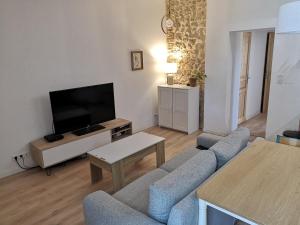 ein Wohnzimmer mit Couch und Flachbildfernseher in der Unterkunft Maison Pittoresque Terrasse et Jardin Monastir del Camp in Passa