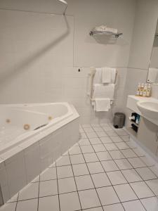 un bagno bianco con vasca e lavandino di Cedar Grove Motor Lodge a Nelson Altre 37 foto