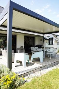 a covered deck with white tables and chairs on it at Magnifique maison de famille - Entre terre et mer in Fouesnant