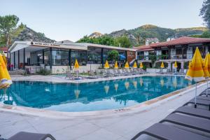a large swimming pool with chairs and umbrellas in front of a hotel at Katre Hotel Oludeniz in Oludeniz