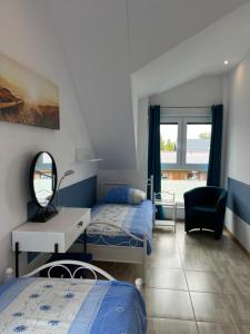 a bedroom with two beds and a desk and a mirror at Apartamenty Kormoran in Sarbinowo
