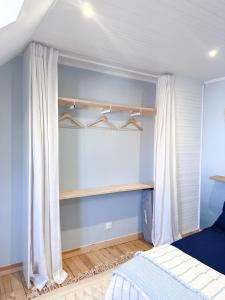 Schlafzimmer mit blauen Wänden, weißen Vorhängen und einem Bett in der Unterkunft L'Heurt Bleue - Maison de pêcheur face mer in Le Portel