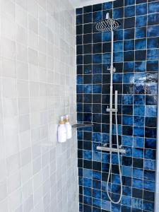 a blue tiled shower with a shower head in a bathroom at L'Heurt Bleue - Maison de pêcheur face mer in Le Portel
