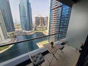 Un balcón con sillas y vista a un río y edificios. en Click Stay - JLT - Entire Studio & Balcony Lakes view Apartment -NA, en Dubái