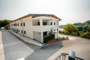 um grande edifício branco com um estacionamento em Danner Appartements Wolfsegg am Hausruck- Ferienwohnung & Business-Appartements Ruhige Lage, moderne Ausstattung, faire Preise em Wolfsegg am Hausruck