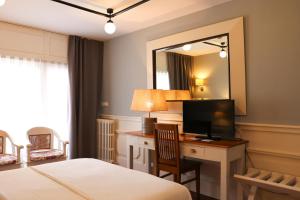 a bedroom with a bed and a desk with a television at Hotel Vostra Llar in Palamós