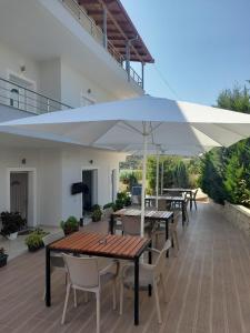 eine Terrasse mit Tischen, Stühlen und Sonnenschirmen in der Unterkunft Vila Ervin First Floor in Ksamil