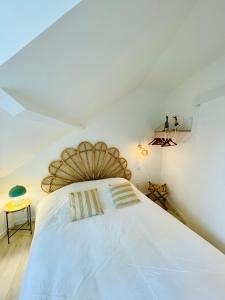 une chambre avec un grand lit blanc avec une tête de lit en bois dans l'établissement Lou & Moi Appartement à 50m de la plage, à Cayeux-sur-Mer