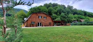 a large wooden house in a field with a yard at Cabana Moldovan Baisoara cu piscina interioara, ciubar, spa in Lunca Largă