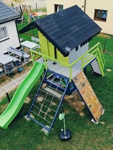 a play structure with a house and a slide at Dom Gościnny Helios in Mielno