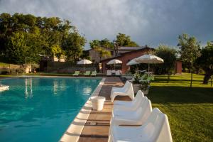 a swimming pool with white chairs and umbrellas at Il Giuggiolo - holiday homes in Fossombrone