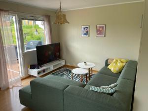 a living room with a green couch and a table at Aurora House under the mountain in Tromsø