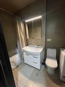 Un baño con un lavabo blanco y un inodoro. en Gldani, en Itʼkhvisi