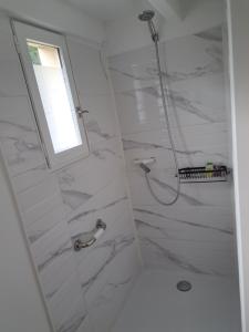 a bathroom with a shower with white marble walls at L A P tite Médocaine in Lesparre-Médoc