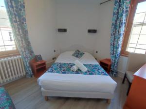 a small bedroom with a bed and two windows at Logis Hotel Restaurant La Croix Verte in Neau