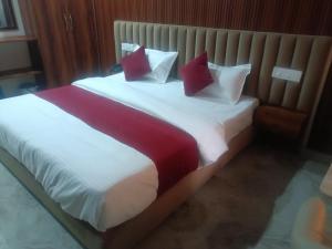 a bedroom with a large bed with red and white pillows at Hotel Noble Stays in Mohali