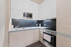 a kitchen with white cabinets and a sink and a microwave at Soukromý Apartmán PVV Pec in Pec pod Sněžkou