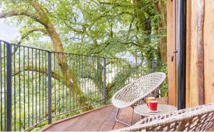 a patio with two chairs and a table on a porch at Treehouse In Devon - riverside woodland hideaway in Beaworthy