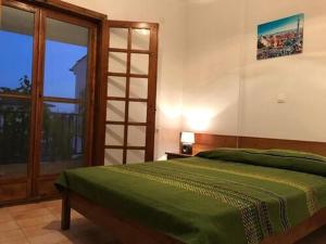 a bedroom with a green bed and a large window at Traditional Bungalows in Kalives Poligirou