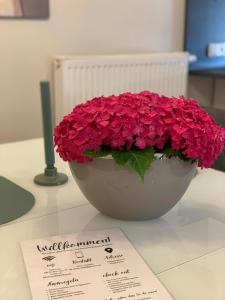 a bowl of red flowers on a table with a note at Ruhrperle Apartment 3 Essen in Essen