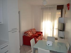 a living room with a red couch and a table at Renovated flat with pool and terrace near the beach in Rosolina Mare