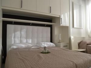 a bedroom with a large bed with a white headboard at Renovated flat with pool and terrace near the beach in Rosolina Mare