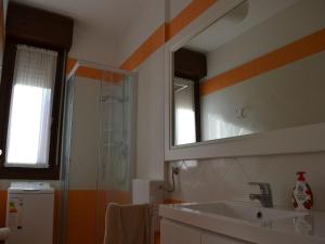 a bathroom with a sink and a mirror and a shower at Renovated flat with pool and terrace near the beach in Rosolina Mare +15 photos