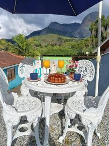 a white table with two chairs and a table with drinks at Casa da Pedra in Pedra Azul