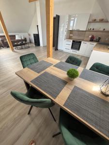 a dining table with green chairs in a room at Apartmán Šumavské nebe in Prachatice