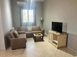 a living room with a couch and a flat screen tv at Kampos Apartment in Chios