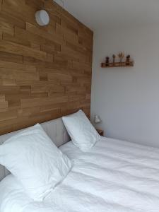 een slaapkamer met een wit bed met een houten hoofdeinde bij Se détendre Au Petit Epi in Turckheim