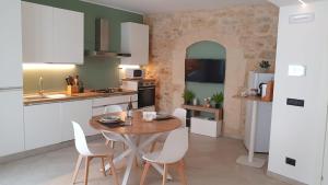 a kitchen with a wooden table and white chairs at Casa Rioda vasca idromassaggio e posizione ideale in Ragusa
