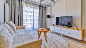 a living room with a couch and a tv and a table at Rezydencja Niechorze D210 z 2 sypialniami Eco Boho - 5D Apartments in Niechorze
