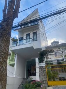 a white house with a tree in front of it at Duy Thảo Hotel in Da Lat