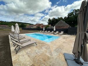 a swimming pool with lounge chairs and umbrellas at Gîte le clocher roman 14 personnes piscine et spa privatif in Bellenot-sous-Pouilly