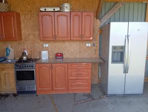 a kitchen with wooden cabinets and a white refrigerator at Peace & Quiet Pole Namiotowo-Kempingowe in Sławoborze