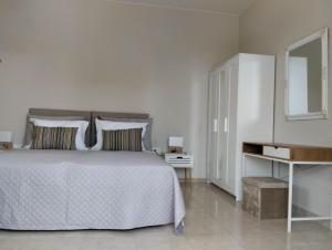 a white bedroom with a white bed and a mirror at Flora Beach House in Kremasti