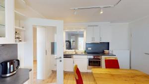 a kitchen with white cabinets and a table with red chairs at Haus Ostwind OSTWIND 'Groot Pläseer' in Langeoog