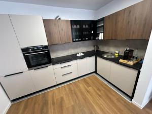 a kitchen with white cabinets and black appliances at Bright flat in Fushë Kosova in Kosovo Polje