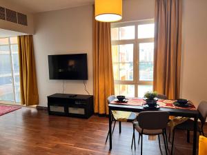 a living room with a table with chairs and a television at ميامي غرفتين مطلة عوائل فقط in King Abdullah Economic City