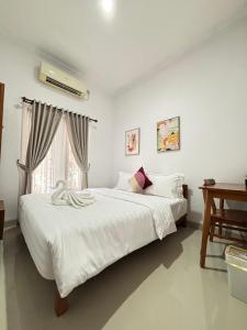 a bedroom with a large white bed and a window at Padma Amita Ambarrukmo in Seturan