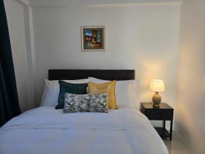 un letto bianco con cuscini e una lampada su un tavolo di Cosy Homes in Suva - Home That Hugs You! a Suva